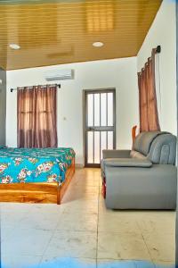 a bedroom with a bed and a couch and a chair at Appartement meublé AKAPEO in Lomé +13 photos