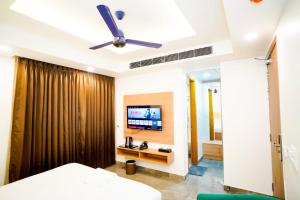 a bedroom with a ceiling fan and a television at Royal Raven Hotel & Banquet' Greater Noida in Greater Noida