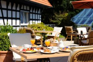 einen Holztisch mit Teller mit Speisen und Getränken in der Unterkunft VILA VITA Burghotel Dinklage in Dinklage