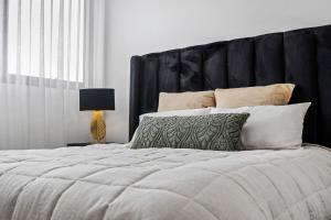 een slaapkamer met een groot bed met een zwart hoofdeinde bij Serene Designer Stay in Sydney