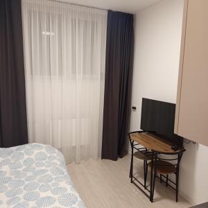 a bedroom with a bed and a desk with a television at VilniusCentralSpot in Vilnius