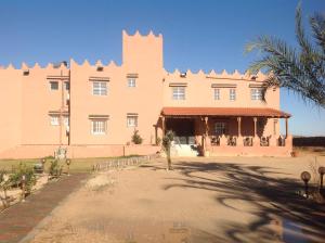 Al Medou的住宿－達爾埃爾菲達歐斯旅館，一座大建筑,前面有棕榈树