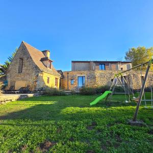 a yard with a swing and a house at Gîte Les Combes Montignac Lascaux in Montignac