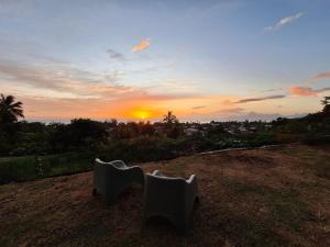 普纳奥亚Fare Pūnano的从山顶上眺望日落,山上摆放着两把白色椅子。