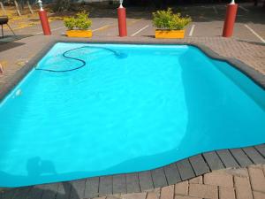 a large blue swimming pool in a parking lot at Grand Central Guesthouse in Rustenburg