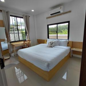 a bedroom with a large white bed and two windows at Baanjaifu บ้านใจฟู in Mukdahan
