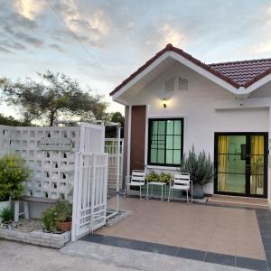 a white house with a fence and chairs at Baanjaifu บ้านใจฟู in Mukdahan