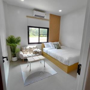 a bedroom with a bed and a couch and a table at Baanjaifu บ้านใจฟู in Mukdahan