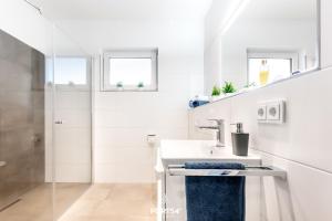 a white bathroom with a sink and a shower at Penthouse Kapitänskajüte, App 25 Olpenitz in Olpenitz