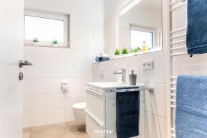 a white bathroom with a sink and a toilet at Penthouse Kapitänskajüte, App 25 Olpenitz in Olpenitz