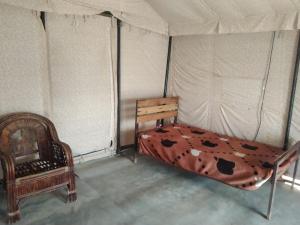 a bedroom with a bed and a chair in a tent at Stayguru Patgar Tent in Dhordo