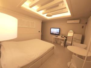 a bedroom with a white bed and a television at 대전 유천 샌디스테이 in Sŏdaejŏnuch'egug-yŏk
