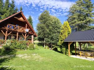 a house with a black roof in a yard at Domek Źródełko in Bystrzyca Kłodzka
