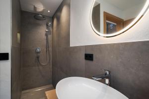 a bathroom with a sink and a shower with a mirror at Chalet Florian in Kirchberg in Tirol