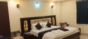 una habitación con una cama grande con sábanas y almohadas blancas en ssr grand residency, en Padappai