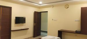 Un baño con un televisor en la pared y un espejo. en ssr grand residency, en Padappai