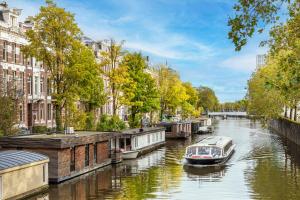 a boat on a river in a city at Amstel Corner Hotel in Amsterdam