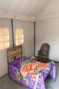 a bedroom with a bed and a chair in a tent at Stayguru Patgar Tent in Dhordo