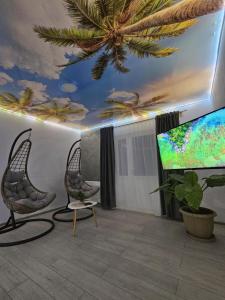 Zimmer mit 2 Stühlen und einem Flachbild-TV in der Unterkunft Vila Kalibu 1 in Iaşi