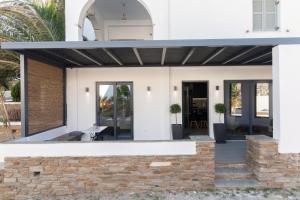 アギオス・イオアニスにあるKlīmaの日よけとレンガの壁のある白い家