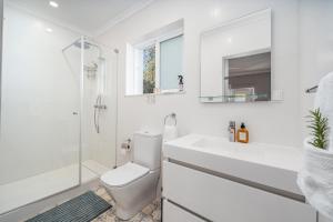 a white bathroom with a toilet and a sink at Orange Blossom Grove in Cerro das Taipas