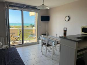 a kitchen with a table and a view of a balcony at Résidence du Golf in Donville-les-Bains