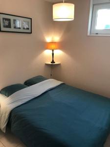 a bedroom with a bed with a lamp on it at Résidence du Golf in Donville-les-Bains