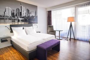 a hotel room with a bed and a purple stool at Tulip Inn Ludwigshafen City in Ludwigshafen am Rhein +19 photos