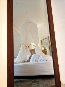 een spiegel die een bed met witte lakens en gordijnen weerspiegelt bij Gusti Ayu Private Bali House - 2 Bedrooms near Kerobokan in Kerobokan