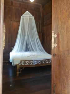 a bed with a net on top of it at Teak House Homestay I in Ban Thung Satong