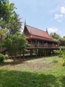 a large building with a deck in a park at Teak House Homestay I in Ban Thung Satong