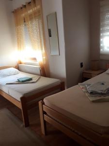 two beds in a small room with a window at VILA NATALIJA APARTMANI in Apatin