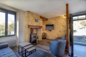 un soggiorno con parete in pietra e TV di Gite De L'école a La Mouline