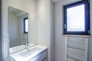 un bagno bianco con lavandino e specchio di Gite De L'école a La Mouline Altre 19 foto