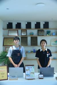 twee jongens staan voor een tafel met laptops bij Qingdao Momer Cliff Ocean View Villas in Qingdao