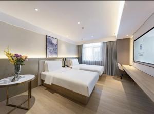 a hotel room with two beds and a flat screen tv at Xingcheng Beijing Huilongguan Jishuitan Hospital Hotel in Beijing