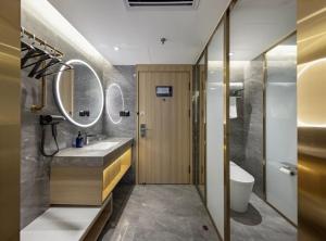 a bathroom with a sink and a toilet and mirrors at Xingcheng Beijing Huilongguan Jishuitan Hospital Hotel in Beijing +27 photos