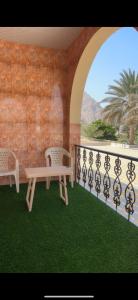 balcón con 2 sillas, mesa y pared en Crestora farm, en Ras al Khaimah