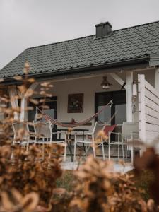 a house with a patio with chairs and a hammock at Kolory Mazur in Stare Jabłonki