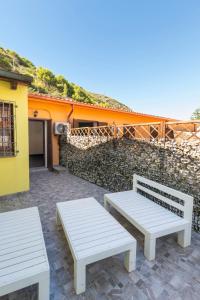 twee witte banken op een terras voor een gebouw bij White Lion SURF & MINE GUESTHOUSE in Buggerru