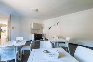 een eetkamer met witte tafels en stoelen bij White Lion SURF & MINE GUESTHOUSE in Buggerru