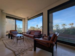 ダル・ブアッザにあるSeafront Luxury Villa with Amazing pool!のリビングルーム(椅子2脚、テーブル付)、大きな窓が備わります。