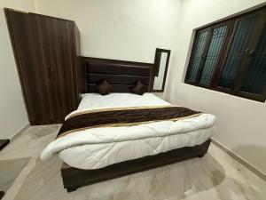 ein Schlafzimmer mit einem großen Bett mit einem hölzernen Kopfteil in der Unterkunft Grand Vista Kashi 2BHK Home in Varanasi