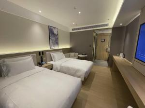 a hotel room with two beds and a flat screen tv at Xingcheng Beijing Huilongguan Jishuitan Hospital Hotel in Beijing