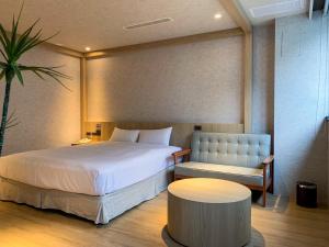 een slaapkamer met een bed, een bank en een tafel bij Fairy Tale City Motel in Hualien