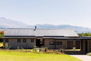 a house with a metal roof with mountains in the background at 3BR Drakensberg Retreat, Mountain Views and Braai in Ardmore