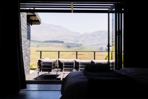 a bedroom with a view of a balcony with chairs at Luxury 4BR Drakensberg Home Private Pool and Braai in Champagne Valley