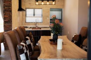 a dining room with a wooden table with flowers on it at Luxury 4BR Drakensberg Home Private Pool and Braai in Champagne Valley