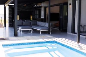 a patio with a couch and a swimming pool at Luxury 4BR Drakensberg Home Private Pool and Braai in Champagne Valley