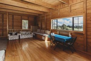 a log cabin with a table and chairs and a window at The River Retreat - off the grid escape in Inglewood